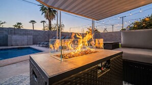 Zona junto a la piscina con un hogar, asientos al aire libre y vistas a la piscina.