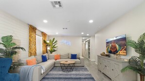 Una sala de estar con sofá, mesa de centro y plantas en macetas.