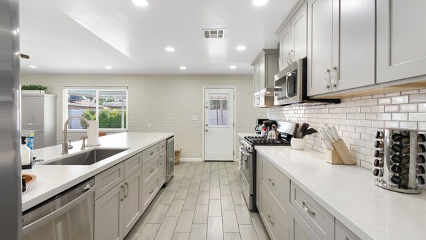 Una cocina moderna con armarios blancos, un refrigerador de acero inoxidable y un salpicadero de azulejos.