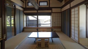 A traditional Japanese room with tatami flooring, sliding doors, and a low table with cushions. - Shimayado Mari (Shodoshima)