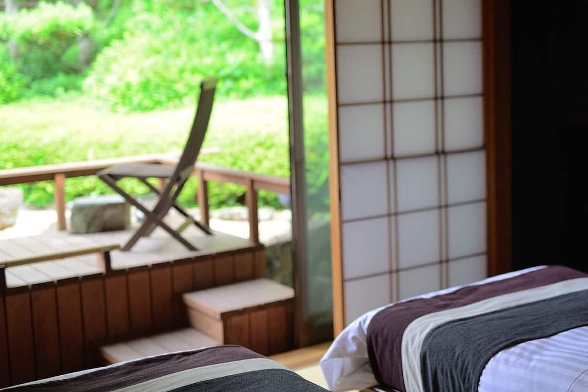 Un dormitorio con vistas a una terraza de madera y vegetación.