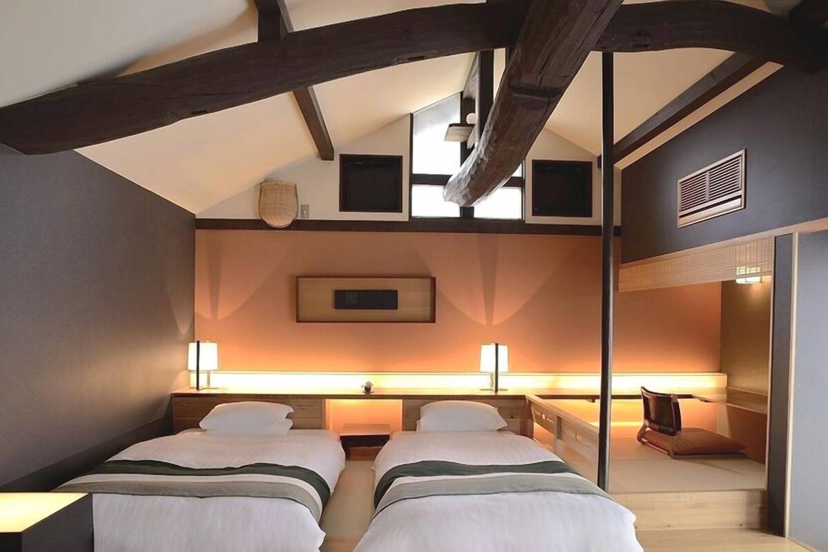 Habitación de hotel con dos camas, un ventanal grande y vistas al cielo.