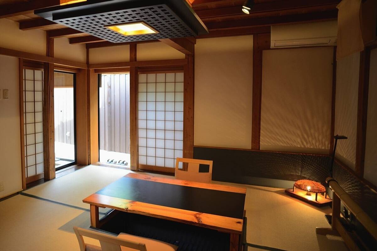 Una habitación japonesa tradicional con suelo de tatami, puertas correderas, una mesa baja y una cama futón.