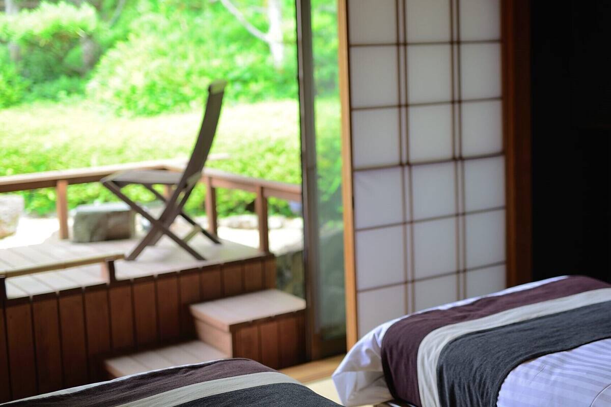 Una habitación con una cama, una terraza de madera y vistas al verdor.