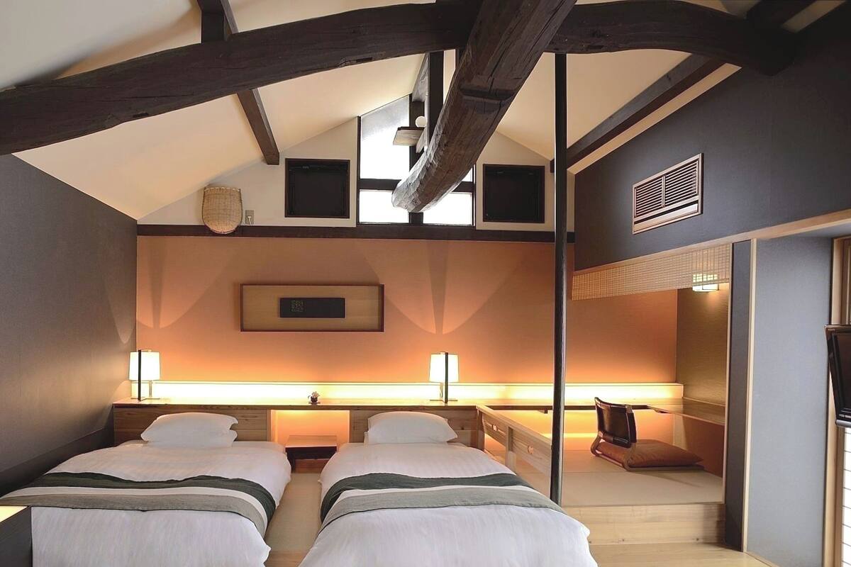 Un dormitorio con dos camas, techo de madera, un cuadro enmarcado en la pared y una ventana.