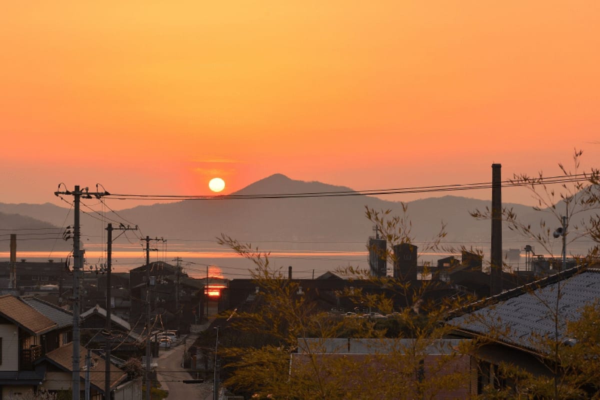 Atardecer sobre un barrio residencial con casas y líneas eléctricas.