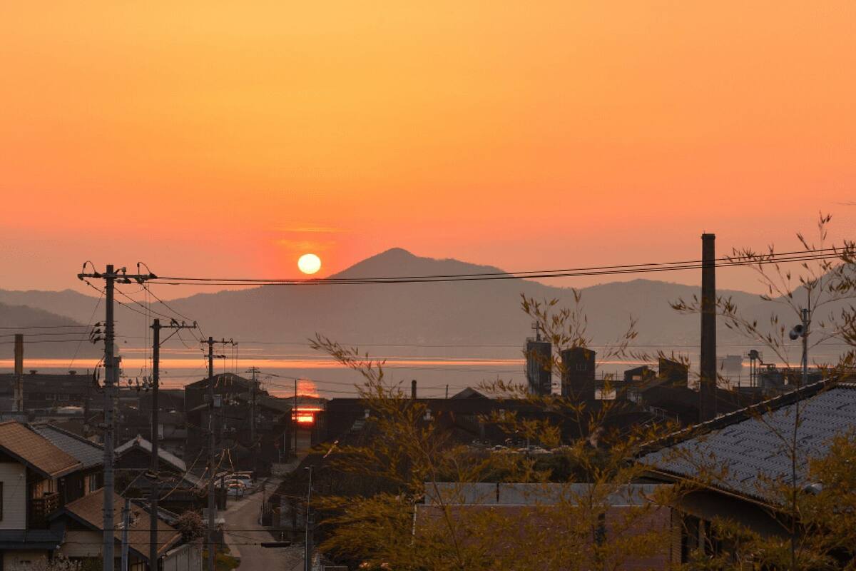 A sunset over a residential area with houses and power lines.