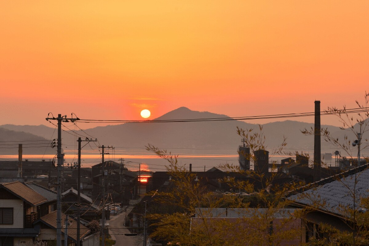 A sunset over a residential area with houses and power lines.