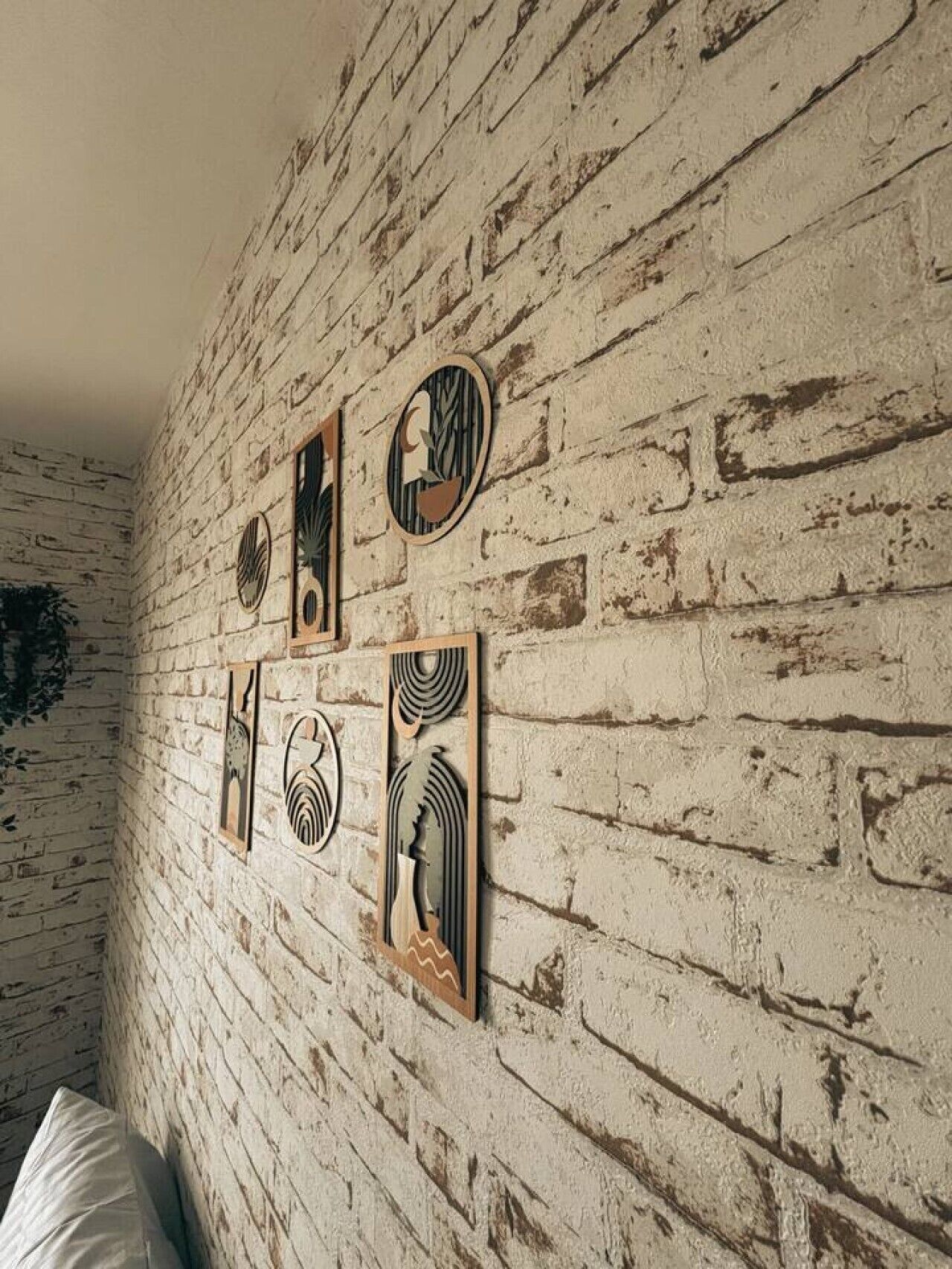 Une pièce avec un mur en briques blanches et quatre œuvres d’art encadrées.