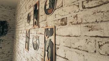 Une pièce avec un mur en briques blanches et quatre œuvres d’art encadrées.