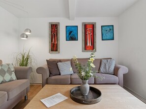 Ein modernes Wohnzimmer mit einer Couch, einem Couchtisch mit Blumenvase und abstrakter Kunst an der Wand.