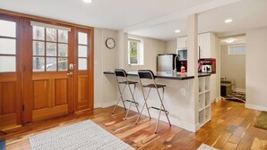 Una cocina compacta con puerta de madera, un reloj y un refrigerador.