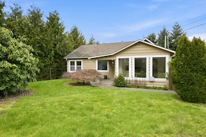 A single-story house with a front porch, a small front yard, and a large window on the front.