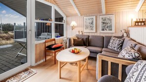 En ombonad inredning med ett träpanelat tak, en matplats med bord och stolar, en soffa och ett stort fönster med fin utsikt.