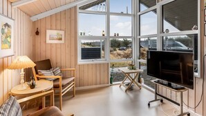 Ett rum med ett stort fönster, en tv, ett bord och en stol.