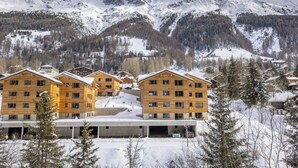Un hotel con diversi edifici in legno, un'area di parcheggio e montagne innevate sullo sfondo.