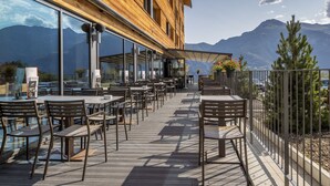 Un edificio in legno con posti a sedere all'aperto e ampie finestre vista montagna.