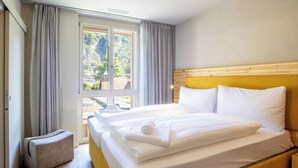 Een hotelkamer met een bed, een zithoekje en een raam met gordijnen.