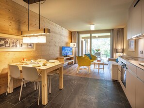 A modern kitchen with a dining area, wooden walls, and a TV. - SWISSPEAK Resorts Meiringen by Interhome (Meiringen)