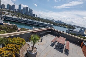 A rooftop terrace with seating, a view of the city skyline, and a harbor with a bridge. - Luxury Seidler Apt, rooftop pool, sweeping views (Potts Point)