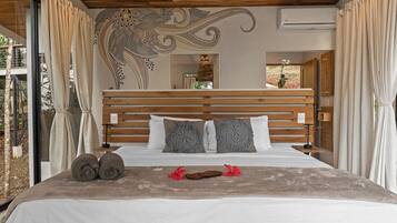 A bedroom with a wooden headboard, a bed with white bedding, decorative pillows, and a view of the outdoors.