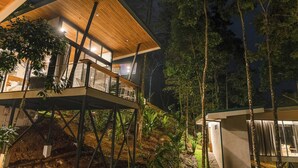 Ein modernes Haus mit einer Holzterrasse, großen Fenstern und Blick auf den umliegenden Wald.