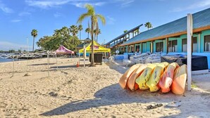 A beachside hotel with a covered seating area, surfboards, and palm trees. - Bahia Beach Calm Ruskin Retreat (Ruskin)