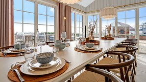 Un comedor con una mesa larga, sillas y ventanas amplias que ofrecen vistas.
