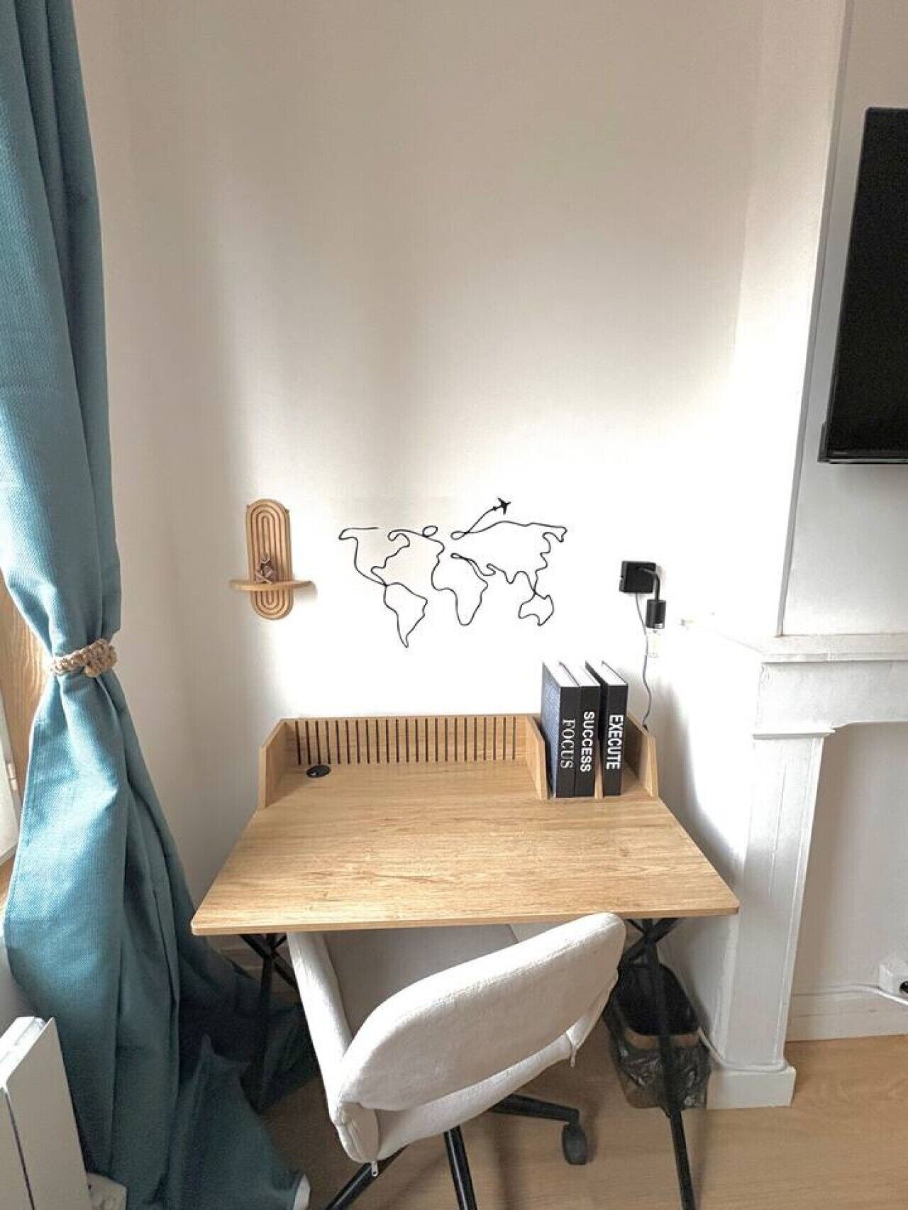 Un espacio de trabajo en esquina con un escritorio de madera, una silla de oficina blanca, un mapa del mundo como decoración de pared, y dos libros titulados 'SUCCESS' y 'FOCUS'.