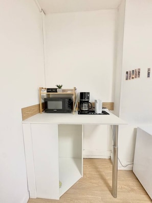 A small kitchenette with a microwave, coffee maker, and a small shelf with a plant. - Studio Dedicated office Autonomous arrival Valenciennes (Valenciennes)