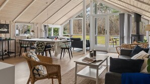 Un espacio interior amplio con techo alto, una mesa de comedor, sillas, un sofá y una chimenea.