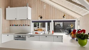 Una cocina moderna con armarios blancos, una isla grande y vistas al exterior.