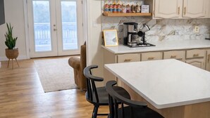 A kitchen with a white countertop, black bar stools, wooden cabinets, and a coffee maker. - Country Home-10 ACRES (Towanda)