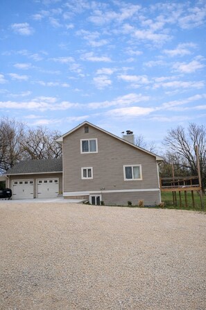 A two-story house with a garage, a gravel driveway, and a fenced yard.