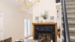 A dining area with a wooden table and chairs, a chandelier, a fireplace, and a staircase. - Country Home-10 ACRES (Towanda)