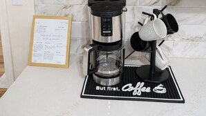 A kitchen with a coffee maker, shelves with coffee bottles, and a sign that says 'Pour some sugar on me.' - Country Home-10 ACRES (Towanda)