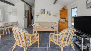 Uma sala de estar com sofá, cadeiras, mesa de centro, televisão e um armário de madeira.