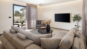 A modern living room with a sofa set, a coffee table, and a TV mounted on the wall. - The Ekfrasis- Mossa Concept Villas (Chania)