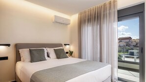 A modern hotel room with a large bed, a balcony with a view of buildings, and a ceiling-mounted air conditioning unit. - The Ekfrasis- Mossa Concept Villas (Chania)