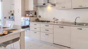 A modern kitchen with a gas stove, stainless steel sink, and light-colored cabinetry. - Casa Carla by Interhome (Gravedona)