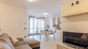 A modern living room with a sofa, TV, and a dining area with chairs and a table. - Casa Carla by Interhome (Gravedona)