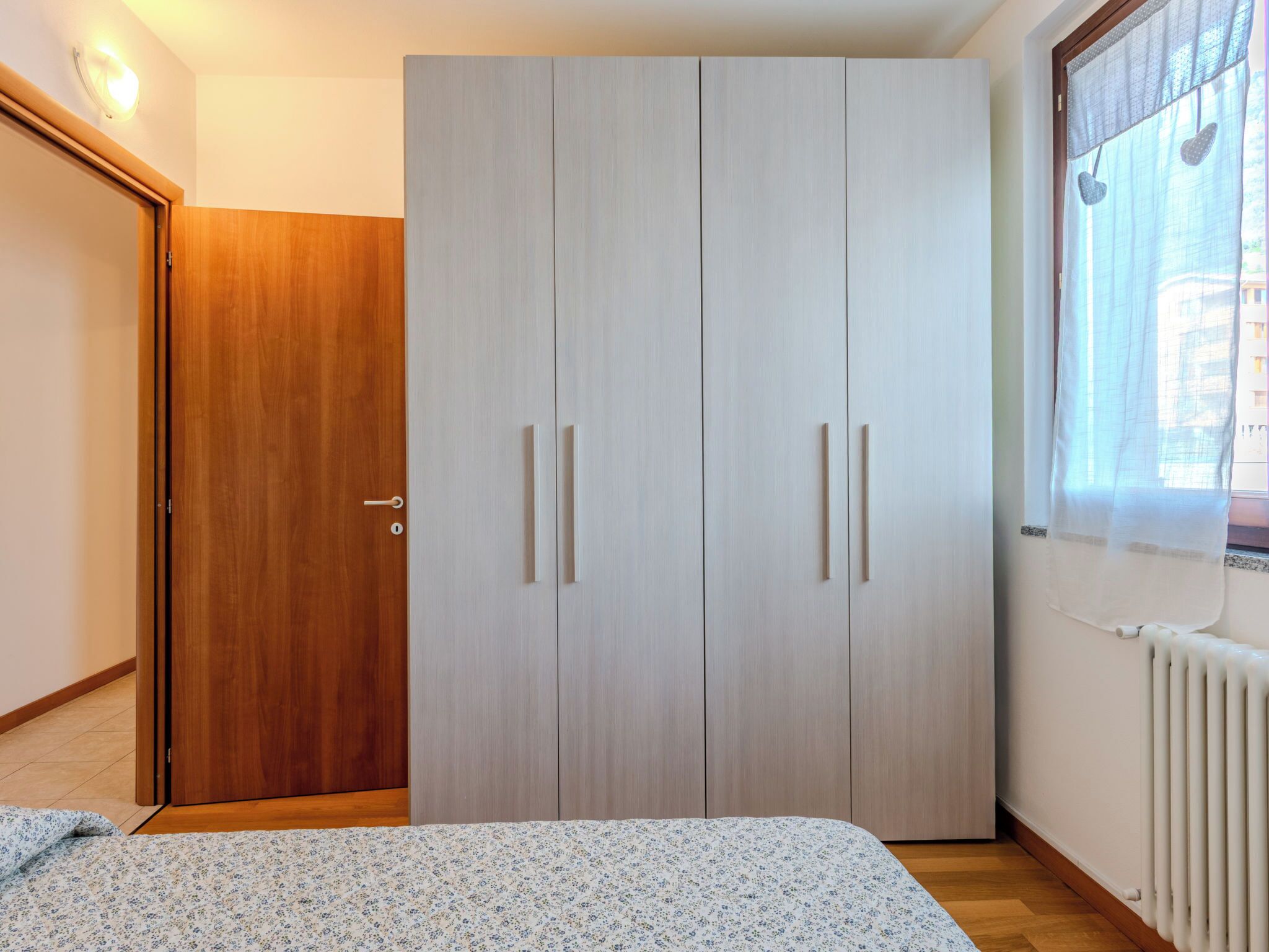Une chambre à coucher avec un lit, une armoire et une fenêtre donnant sur un beau paysage.