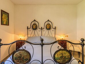 A bed with a metal frame, two wall-mounted lamps, and two framed pictures above the bed. - Casa Aldes by Interhome (Gravedona)