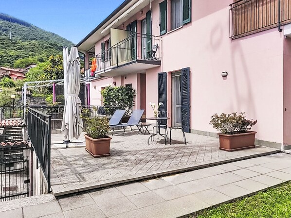 A pink building with a balcony, outdoor seating, and potted plants. - Casa Aldes by Interhome (Gravedona)