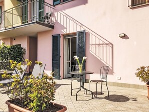 An outdoor patio with a table and chairs, a potted plant, and a building with a balcony. - Casa Aldes by Interhome (Gravedona)