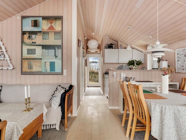 A cozy interior with a dining area, kitchen, and a large painting on the wall.