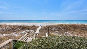 A beach pathway leading to the ocean, surrounded by vegetation.