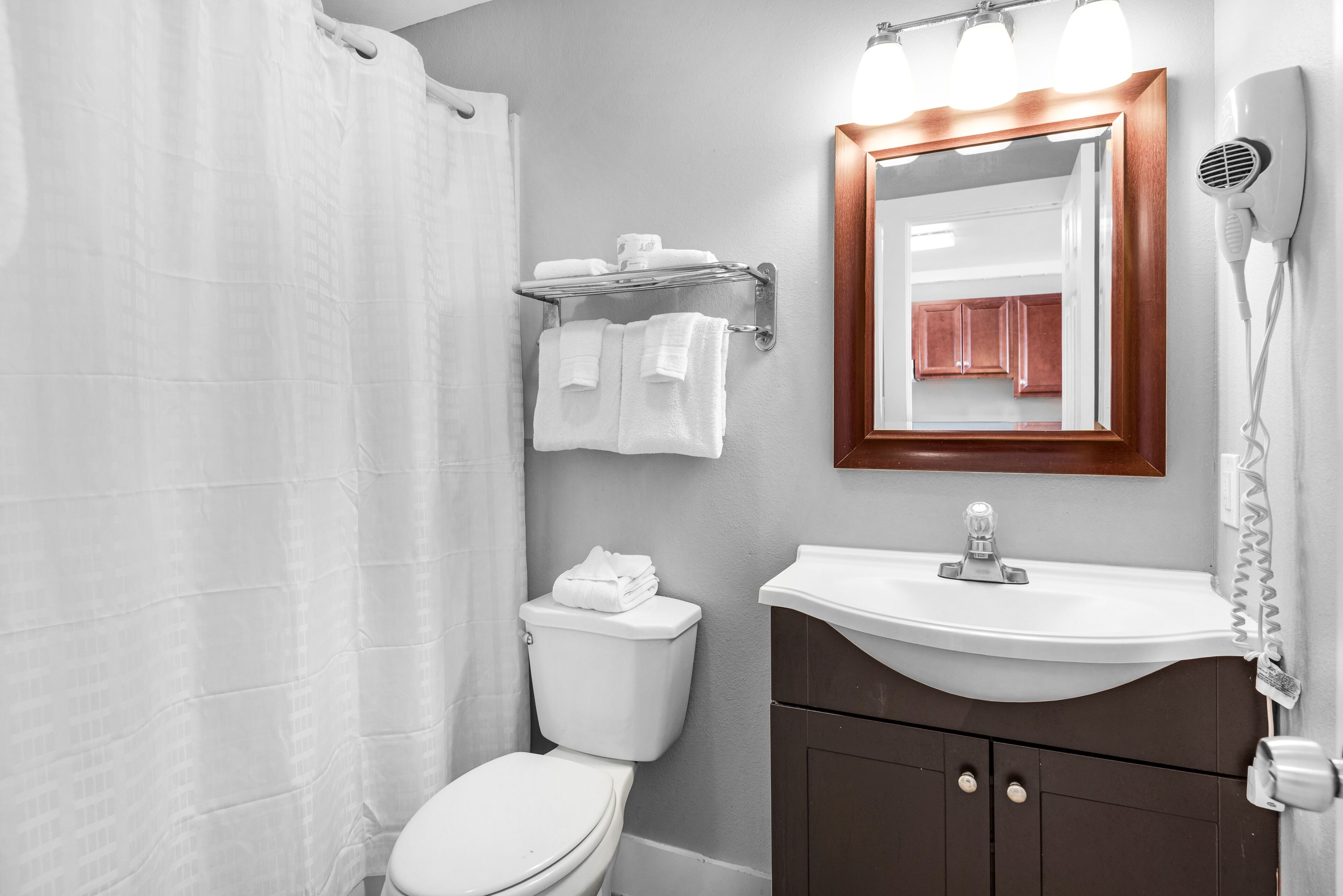 A bathroom with a toilet, a sink, a mirror, a towel rack, and a hairdryer.