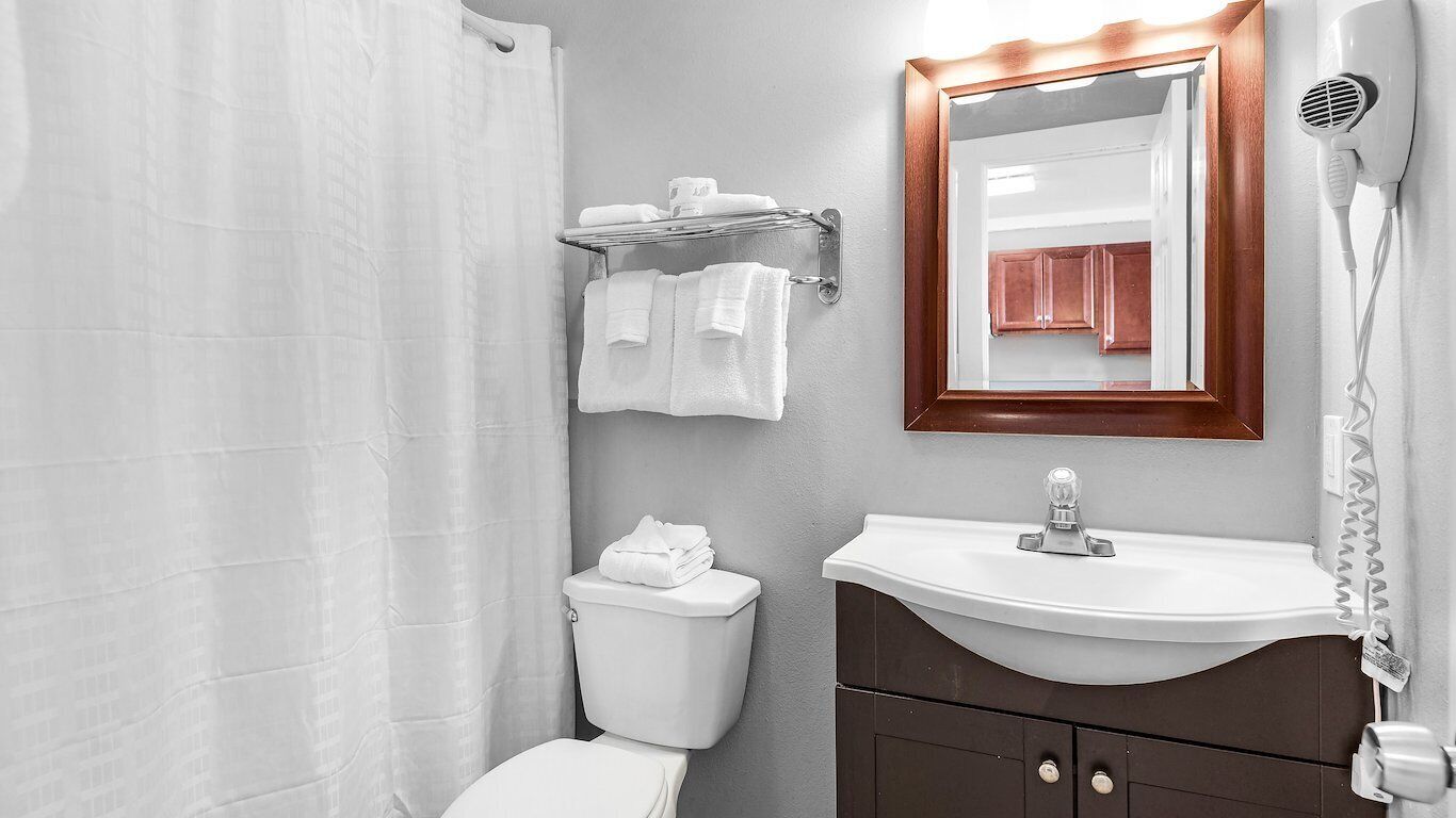 A bathroom with a toilet, sink, and a hairdryer mounted on the wall.
