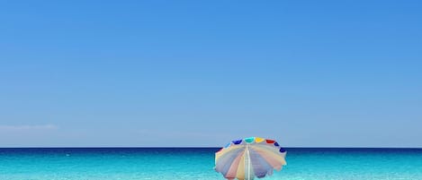 A beach scene with a colorful umbrella and two beach chairs.